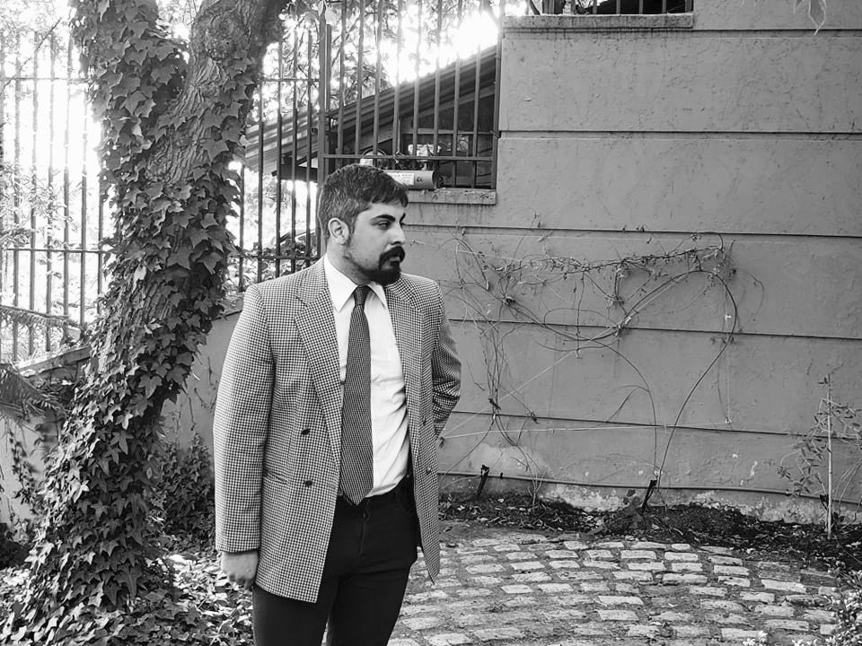 "Escombrario", de Nicolás López-Pérez: La representación de una suma Nicolás López-Pérez en blanco y negro, de pie frente a muro de piedra con hiedra y puerta metálica