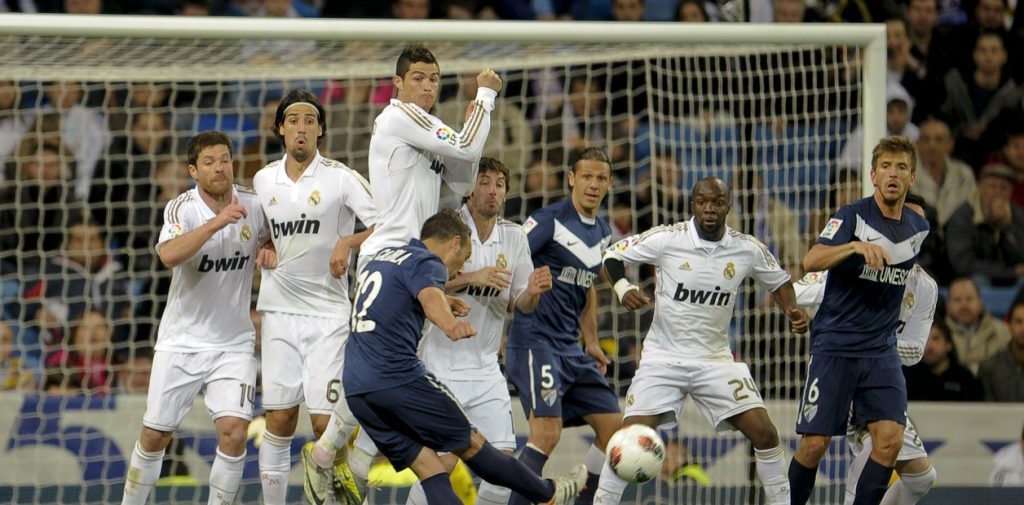 "Un escéptico irremediable": El pavoroso misterio a la caducidad y a la muerte Jugadores de fútbol en blanco y azul disputan el balón cerca del área durante un partido intenso