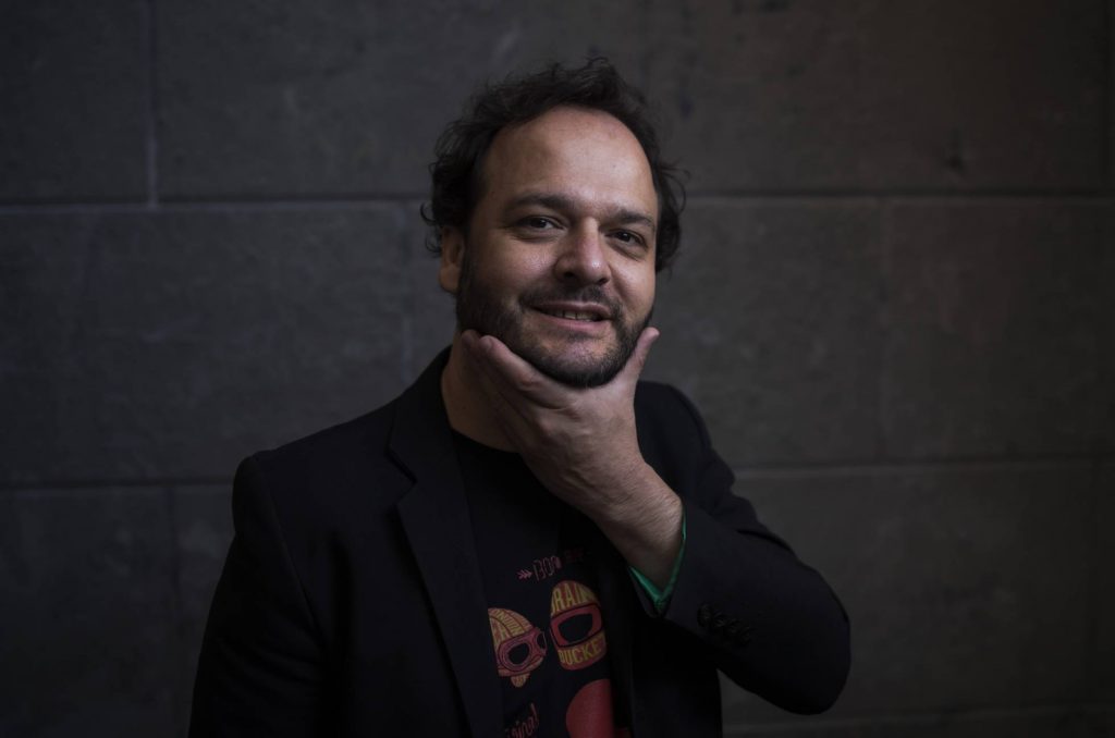 Juan Cárdenas, escritor colombiano, retratado en primer plano con expresión contemplativa, vistiendo abrigo negro