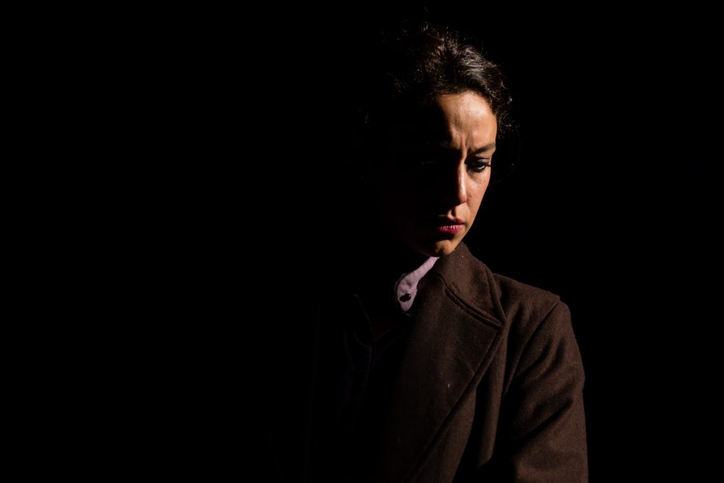 Hombre de perfil en penumbra, iluminación lateral dramática, expresión seria contra fondo negro oscuro