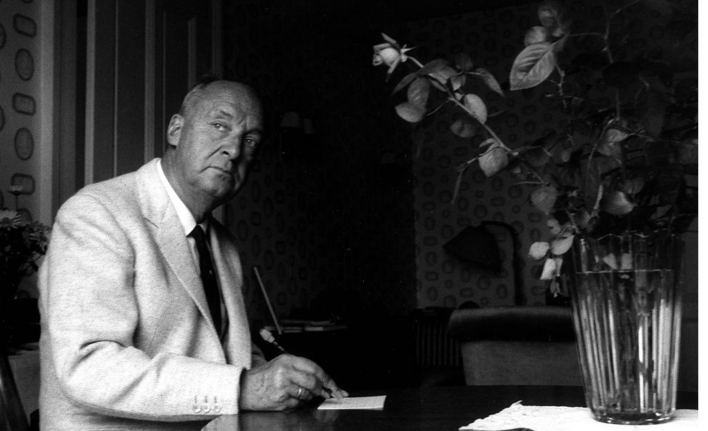 "Lolita", de Vladimir Nabokov: La pasión por lo prohibido Vladimir Nabokov sentado en escritorio con flores, durante entrevista o sesión fotográfica en blanco y negro