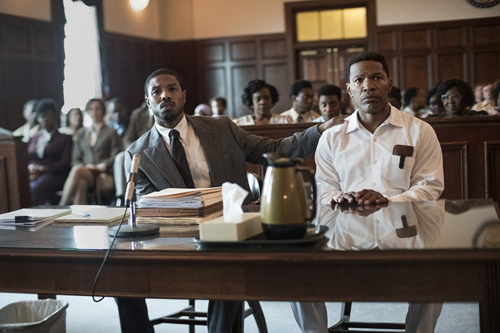 "Buscando justicia": Una invitación para ver lo valioso Hombre afroamericano en traje blanco de pie en sala de tribunal, con micrófono, junto a abogado durante juicio