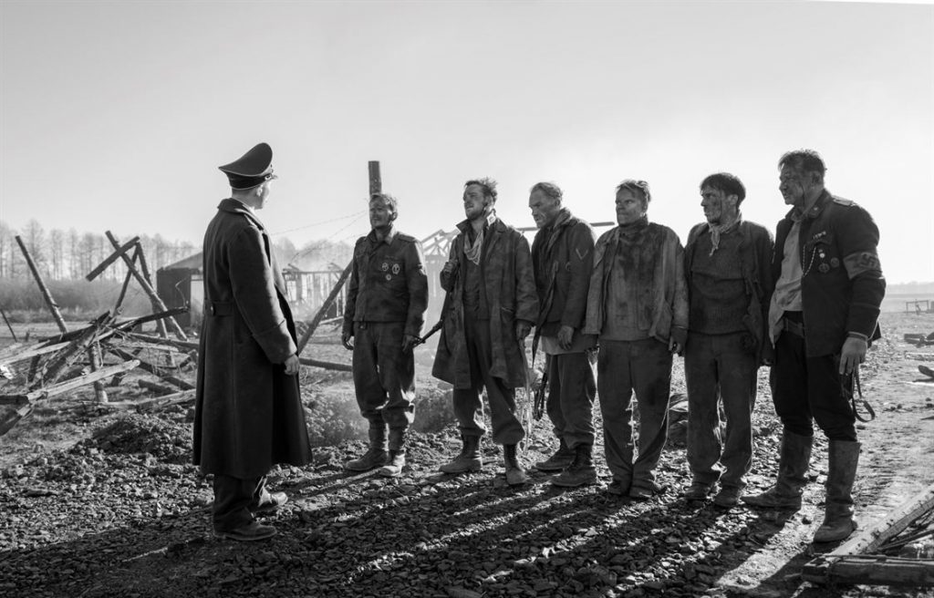 Cine de mundos en peligro: "El capitán", antes del fin Grupo de soldados en uniforme militar de posguerra en terreno árido y desolado, conversando con oficial de rango