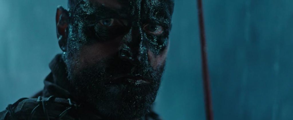 Cine de mundos en peligro: "El planeta de los simios: La guerra", los daños se hallan bajo la piel Rostro de criatura simia cubierto de barro y cicatrices en tonos azulados, expresión intensa y mirada penetrante