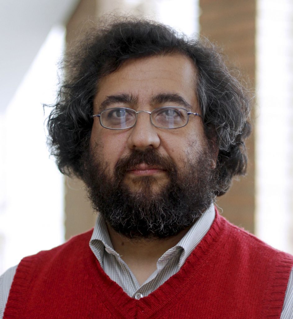 Ismael Gavilán, poeta y escritor chileno, retrato frontal con barba, gafas y suéter rojo