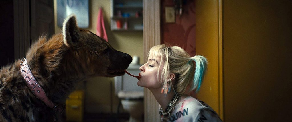 "Aves de presa" y "Joker": Tragedia y comedia en la generación Z Margot Robbie cara a cara con un perro de raza mixta en interior con puerta amarilla de fondo