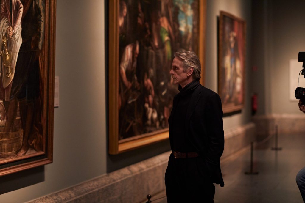 "Pintores y reyes del Prado": El documental que celebra los 200 años del museo español llega a Chile Hombre adulto contemplando pinturas clásicas en galería del Museo del Prado, iluminación cálida