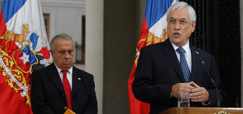 Sebastián Piñera y Jaime Mañalich en podio con bandera chilena de fondo durante conferencia de prensa