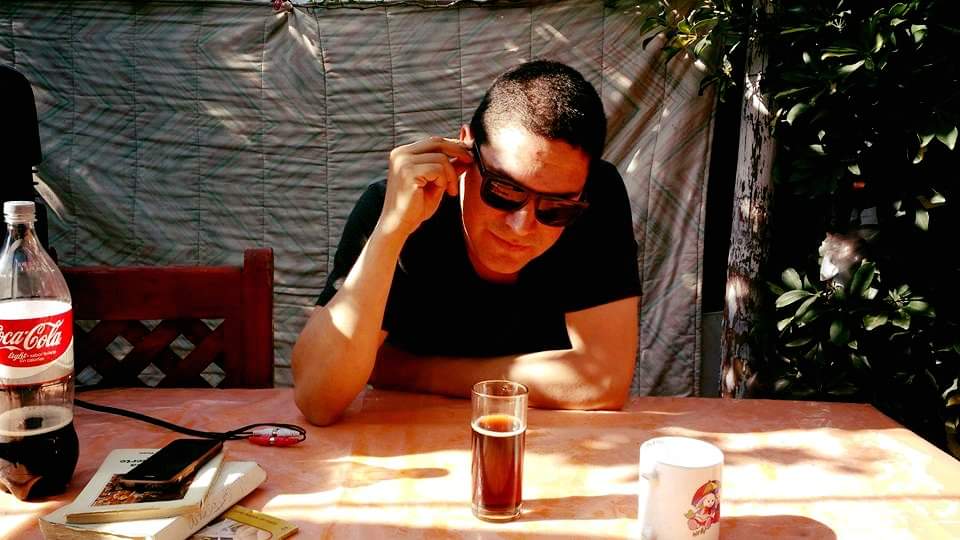 "Las pieles", de Ramón Muñoz Vela: Las cicatrices de la vida Ramón Muñoz Vela en primer plano, con gafas de sol, descansando la cabeza en su mano mientras observa documentos
