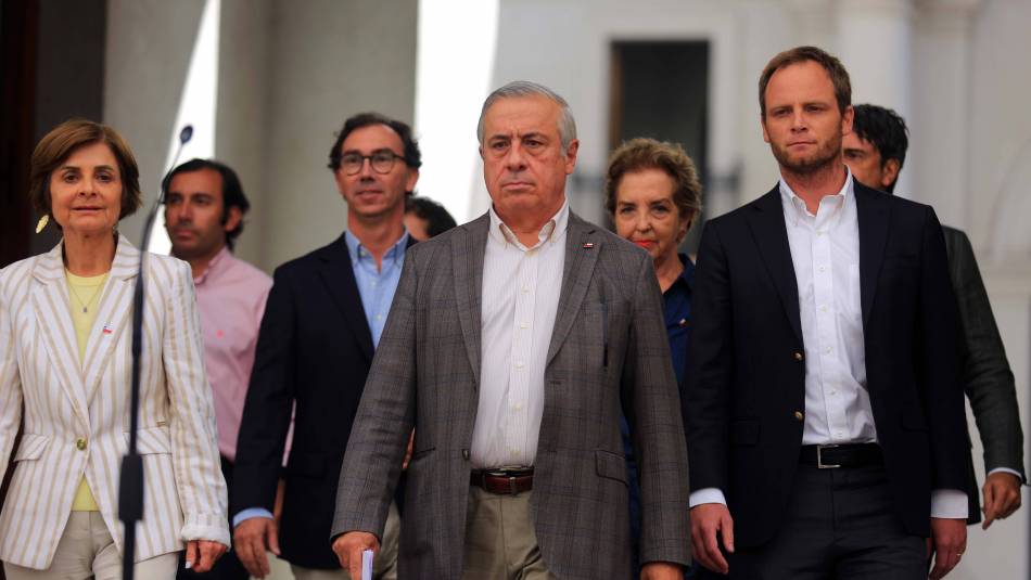 Jaime Mañalich camina entre colegas en pasillo de edificio institucional durante evento oficial