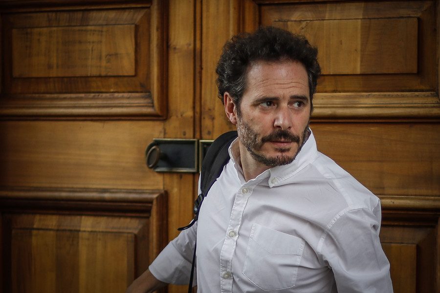 Los nuevos carceleros de un país en cuarentena Hernán Larraín Matte, hombre de mediana edad con barba, vistiendo camisa blanca, frente a puertas de madera