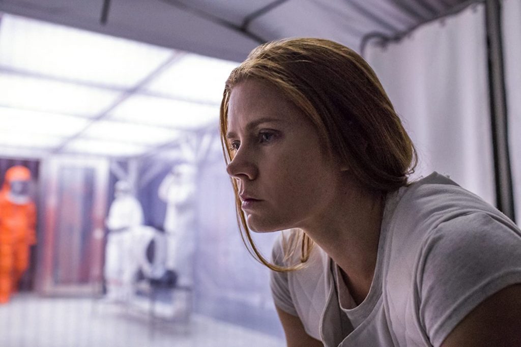 "La llegada", de Denis Villeneuve: Las emociones del tiempo Mujer con cabello castaño observa a través de cristal en interior minimalista iluminado, expresión concentrada