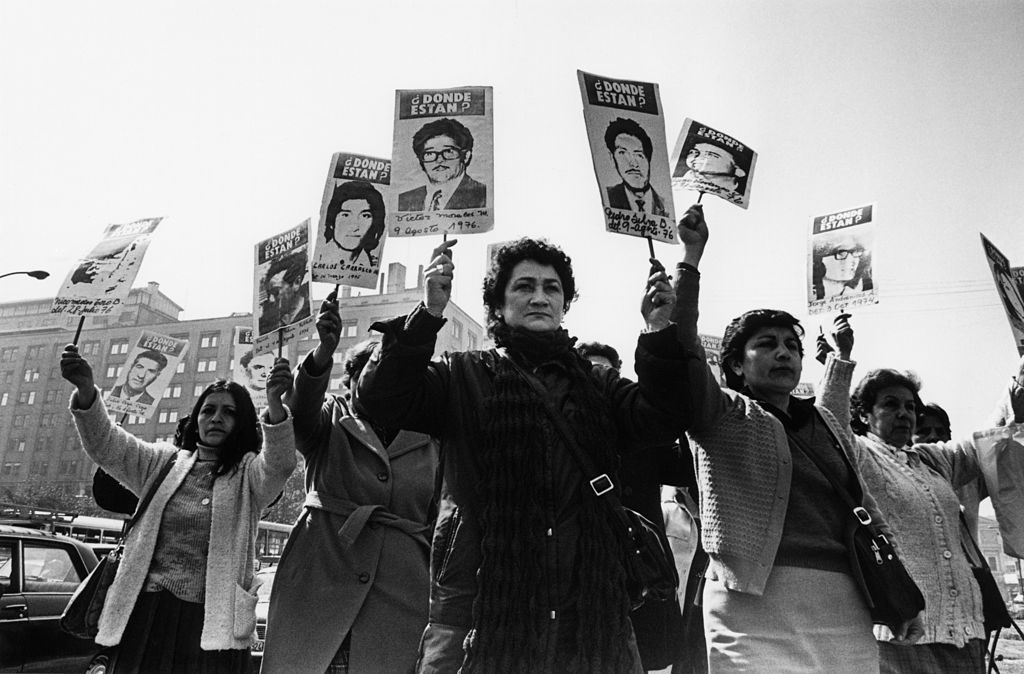 Familiares de detenidos desaparecidos sostienen retratos en manifestación, Chile, años 70