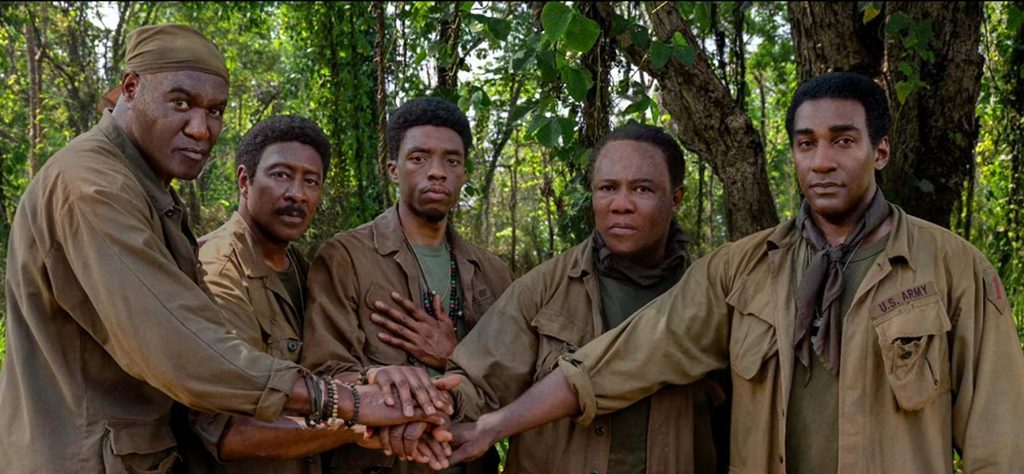 "Da 5 Bloods" ("Hermanos de armas"): La pandemia del racismo estadounidense, filmada por Spike Lee Cinco hombres en uniforme militar en la selva colocan sus manos juntas en gesto de unidad y camaradería