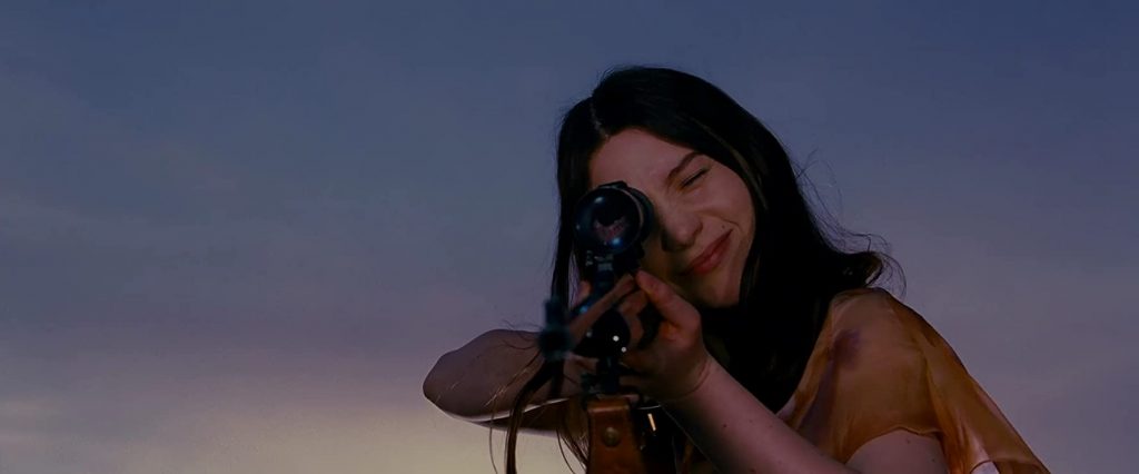 Mujer sostiene cámara de cine profesional frente a su rostro al atardecer