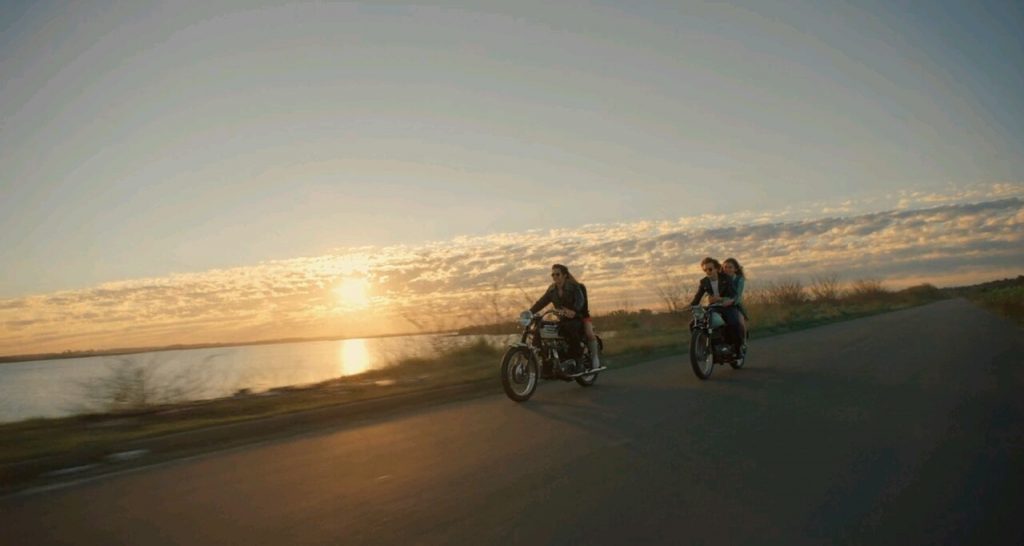 "El ángel", de Luis Ortega: Una estética de la violencia Dos motociclistas en una playa al atardecer, silueteados contra el horizonte dorado del mar