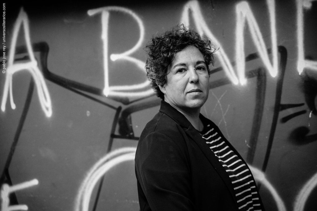 "Las aventuras de la China Iron": La novela que renovó la tradición literaria en Argentina Gabriela Cabezón Cámara, autora de Las aventuras de la China Iron, retratada en blanco y negro frente a un mural