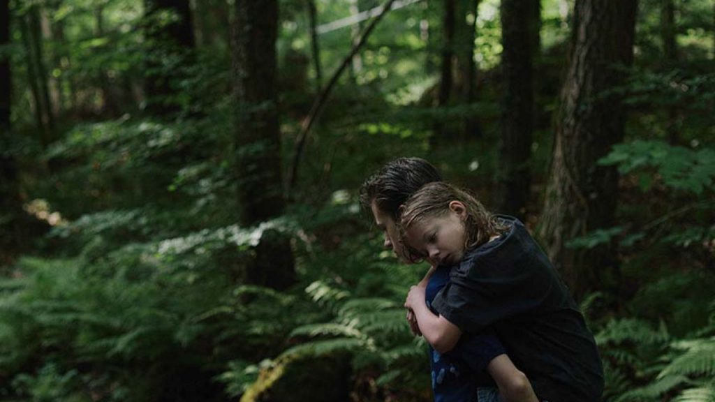 “Estaba en casa, pero”: El filme que protagonizó la controversia en la cartelera europea 2019 Hombre en bosque denso vistiendo chaqueta negra, observando atentamente su entorno entre árboles y vegetación