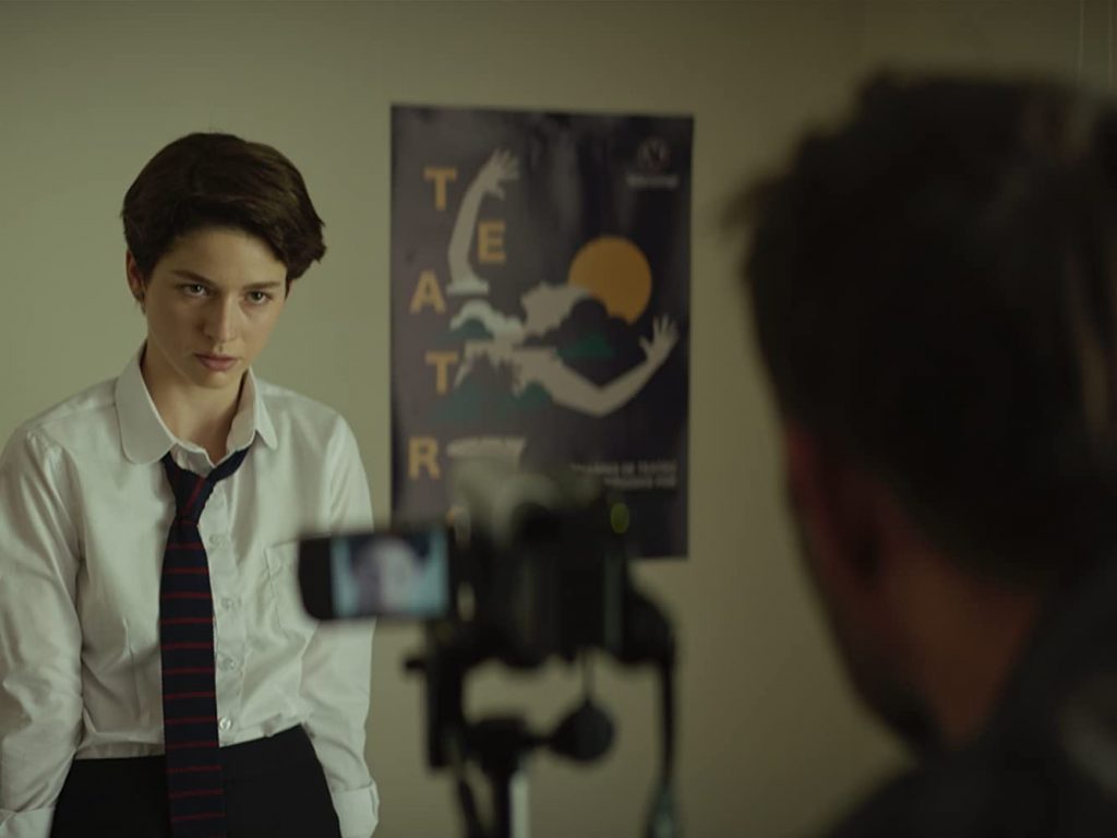 "La jauría": En ese Chile "irreal" de la productora Fábula Joven de lentes y camisa blanca con corbata oscura ante una cámara de cine en set de producción