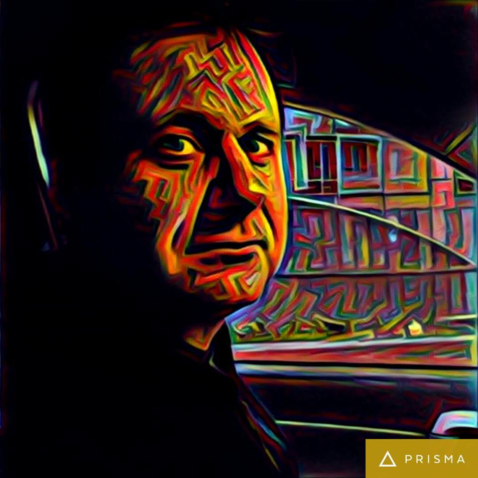 Retrato expresivo de Aníbal Ricci con trazos de color naranja y amarillo, fondo con edificio colorido de estilo urbano