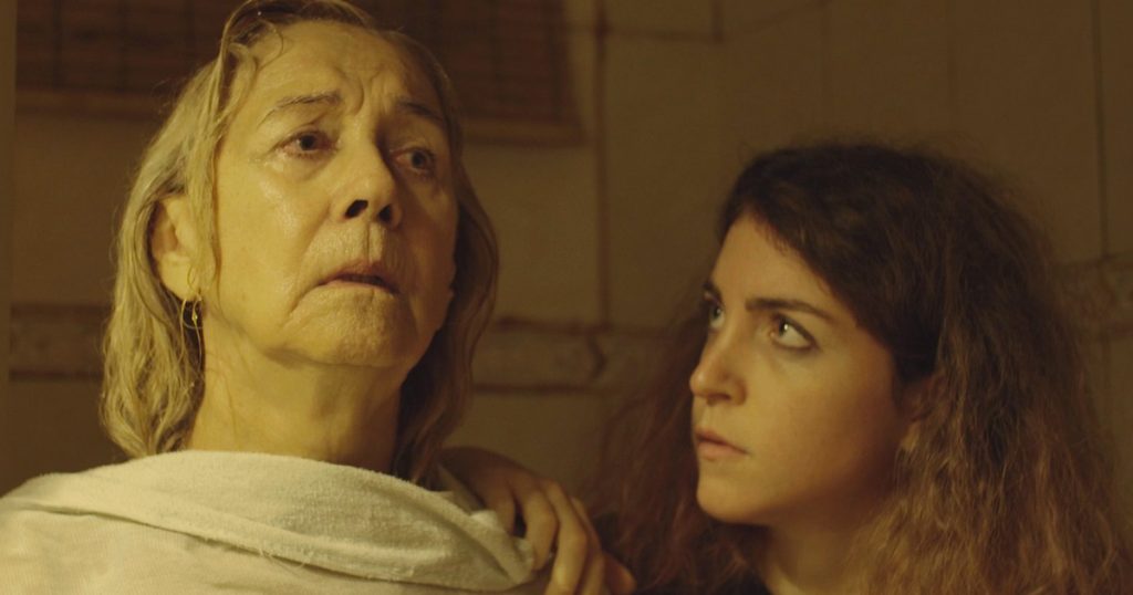SANFIC 16: "Las mujeres de mi casa", un filme para interpelar al Chile cotidiano Dos mujeres en interiores iluminados tenuemente; la de mayor edad mira hacia arriba pensativa mientras la joven observa