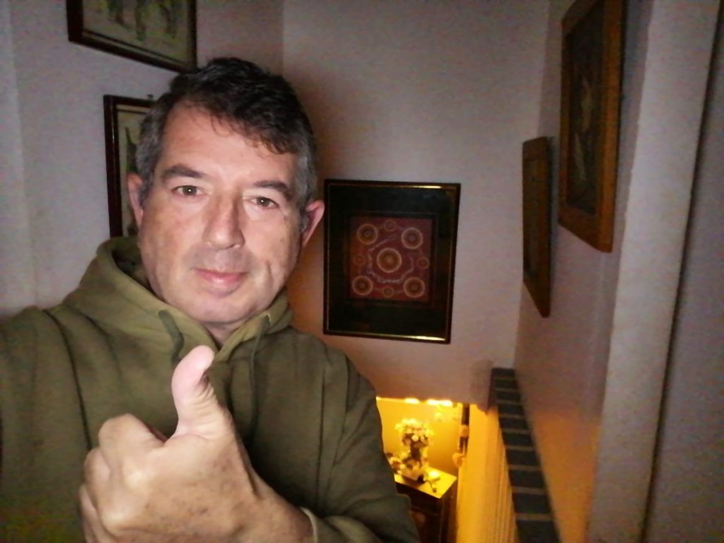 Sergio Moya, profesor de literatura, en interior con cuadros decorativos y objetos amarillos al fondo