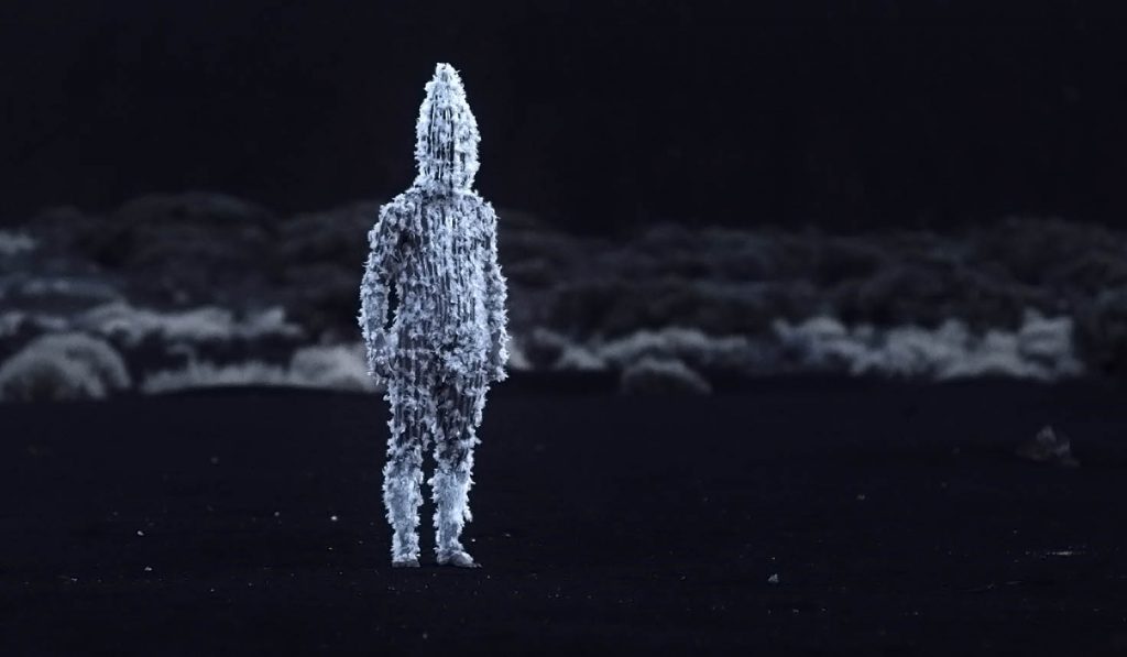 SANFIC 16: "Blanco en blanco", corazón de las tinieblas Figura humana digitalizada en tonos azules y blancos contra fondo oscuro, representando la identidad fragmentada