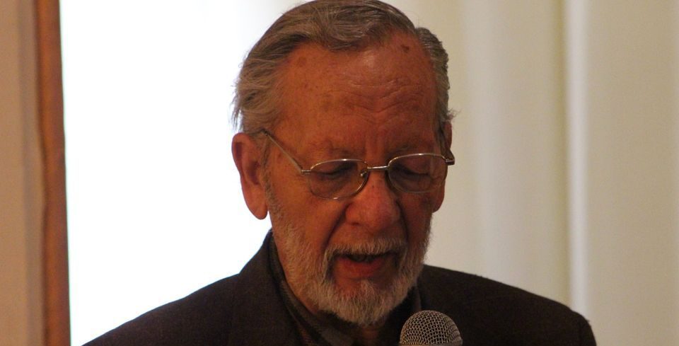 Hernán Ortega, escritor chileno, durante una presentación con micrófono y gafas