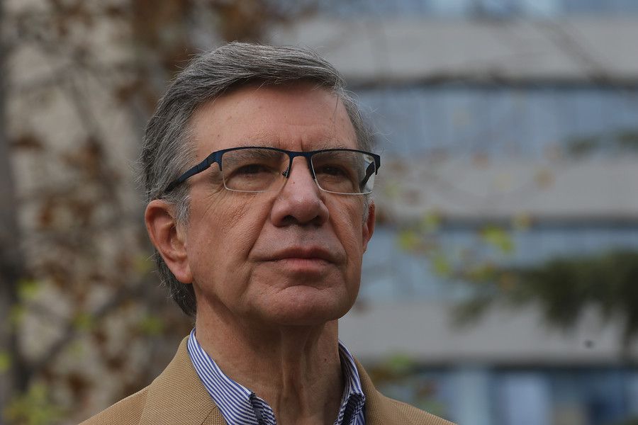 Joaquín Lavín, hombre de mediana edad con gafas y cabello gris, retrato al aire libre con edificios al fondo
