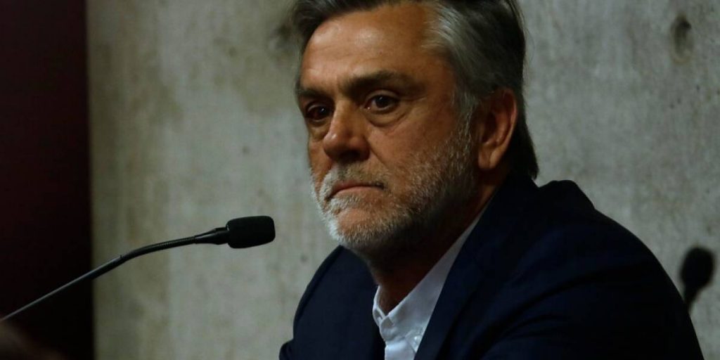 El regreso de los muertos vivientes Pablo Longueira, hombre de mediana edad con barba, habla ante micrófono en evento cultural