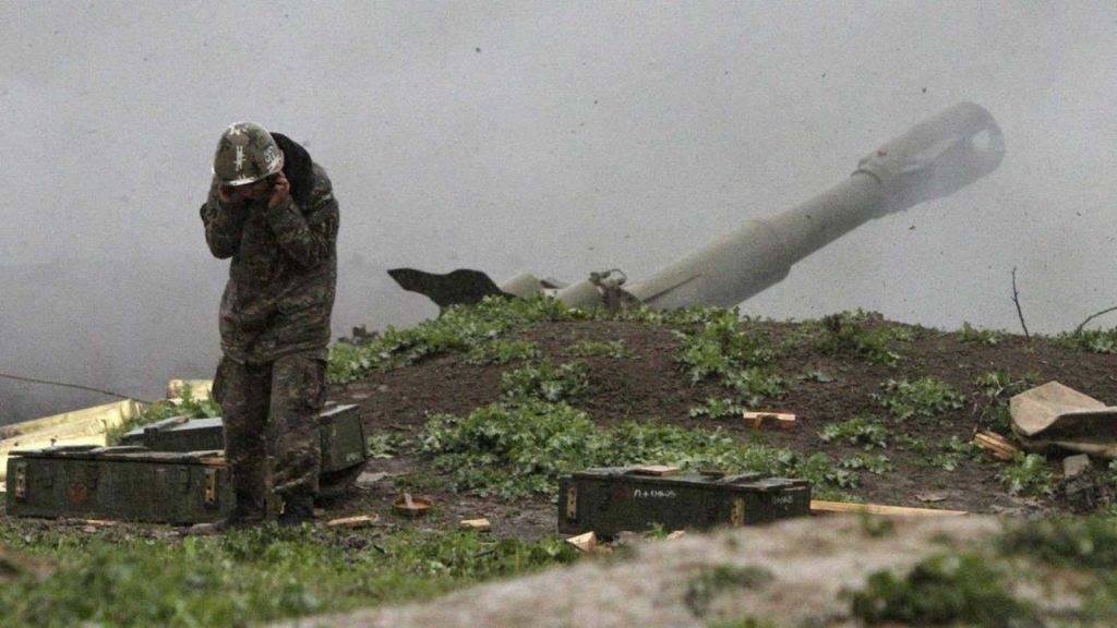 Soldado junto a cañón militar en terreno montañoso cubierto de vegetación en zona de conflicto armenio