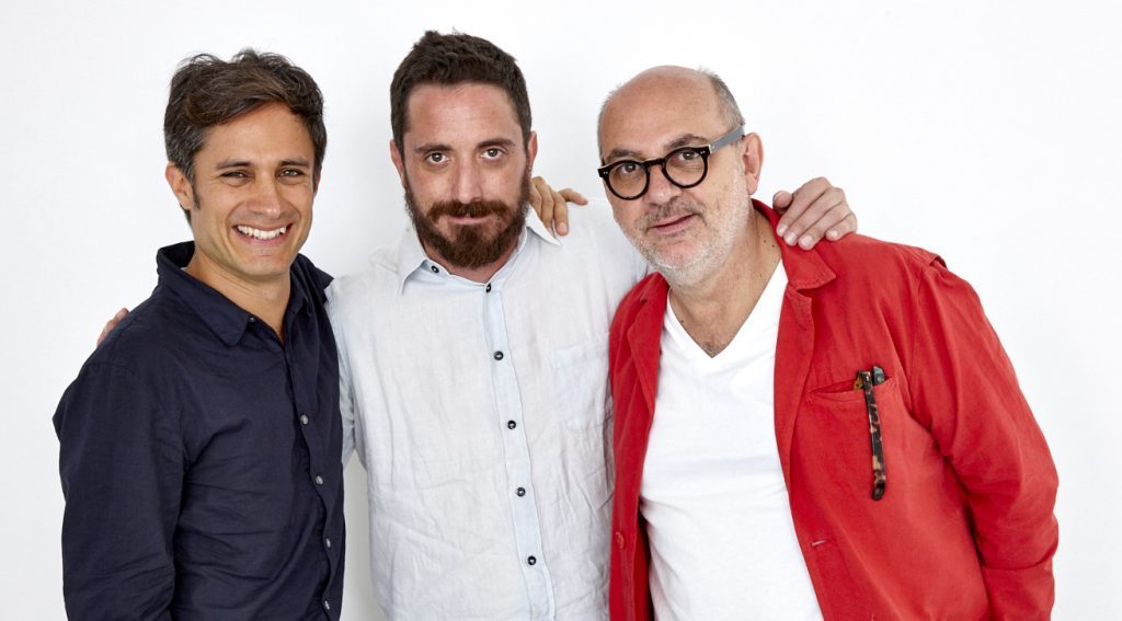 "Neruda", de Pablo Larraín: Las trampas creativas de un cine "fáctico" Tres hombres posan juntos ante cámara: uno de camisa blanca en el centro, flanqueado por un hombre de chaqueta azul