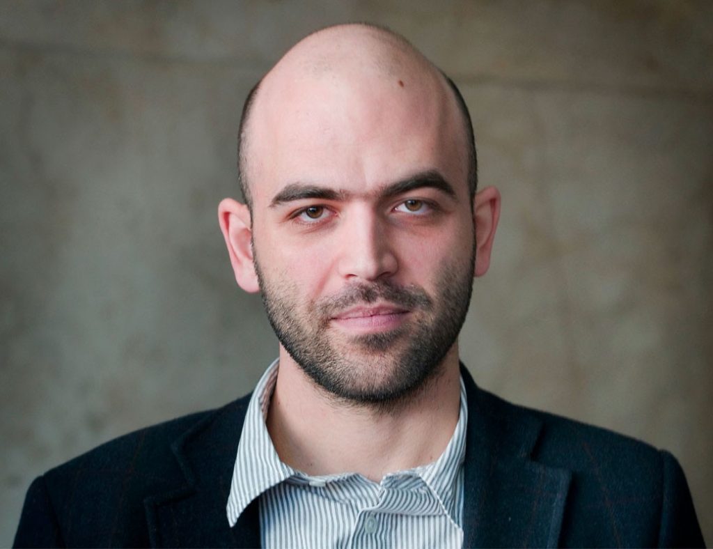 "Beso feroz": La literatura de Roberto Saviano después de "Gomorra" Roberto Saviano, escritor italiano, retrato formal de busto con traje oscuro y camisa a rayas