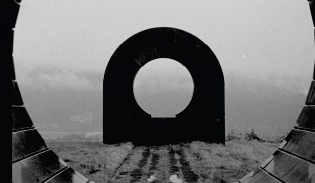 Túnel ferroviario con forma de ojo circular, vías de tren convergentes en perspectiva, cielo gris y desolado