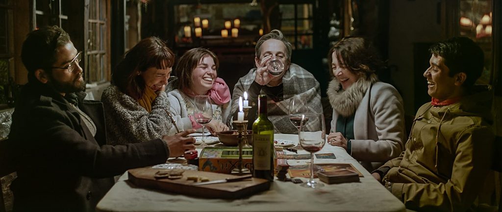 Familia reunida alrededor de una mesa durante una cena, en escena de tensión dramática con iluminación cálida