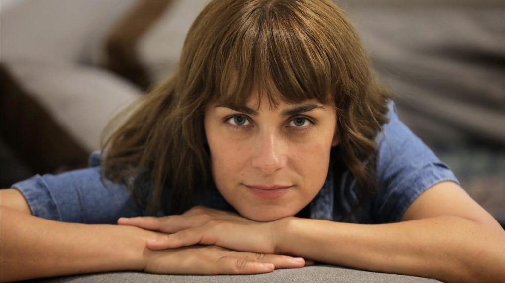 Escritora Sara Mesa apoyada sobre sus brazos, mirando directamente a la cámara con expresión serena
