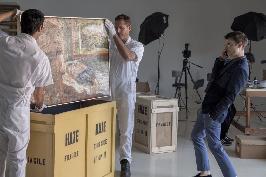 Persona observa cuadro en galería de arte mientras fotógrafo captura la escena con equipo profesional