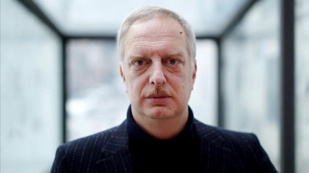 Antonio Scurati, escritor italiano, retrato de frente en ambiente interior moderno con cristaleras al fondo