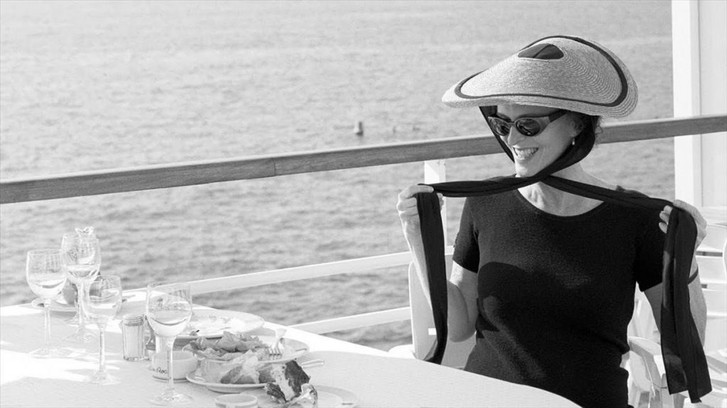 Mujer de perfil con sombrero vaquero sentada junto a una ventana con vista al paisaje desértico