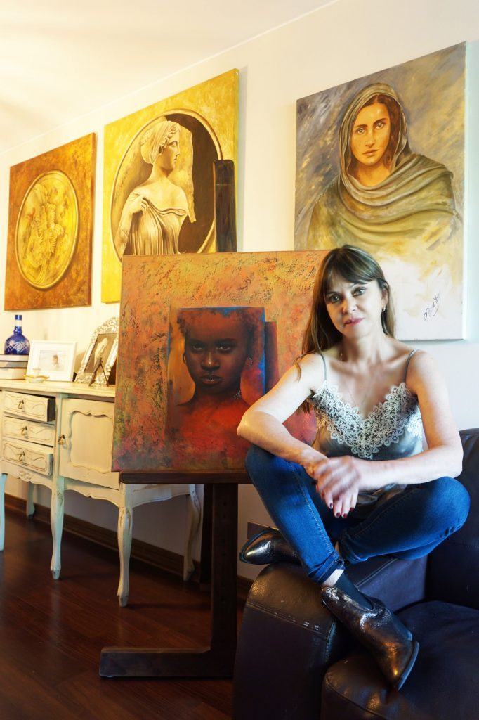 Carmen Pérez Meyer posa junto a obras de arte religioso y un cuadro rojo en su estudio