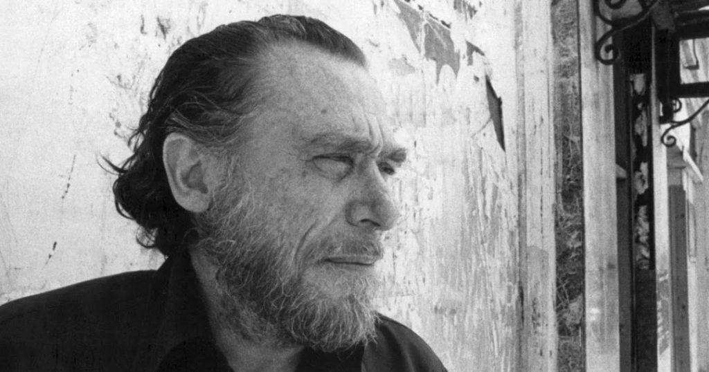 Charles Bukowski, escritor estadounidense, de perfil en blanco y negro contra pared desgastada