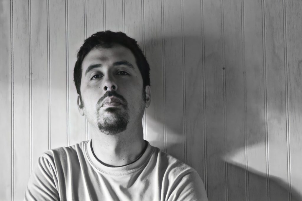 Retrato en blanco y negro de Miguel Eduardo Boìrquez, autor, mirando hacia arriba con expresión pensativa