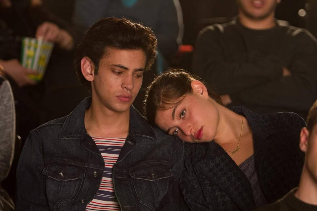 Dos jóvenes sentados juntos en una sala de cine, con expresión contemplativa durante una proyección