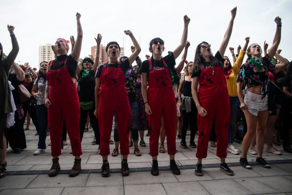 Colectivo Lastesis con brazos en alto vistiendo trajes rojos durante manifestación feminista callejera