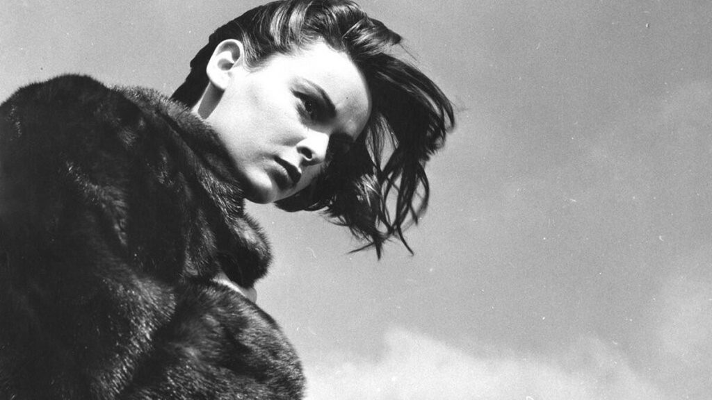 Lucía Bosé con expresión melancólica, fotografía en blanco y negro de los años 50, perfil de actriz española con abrigo