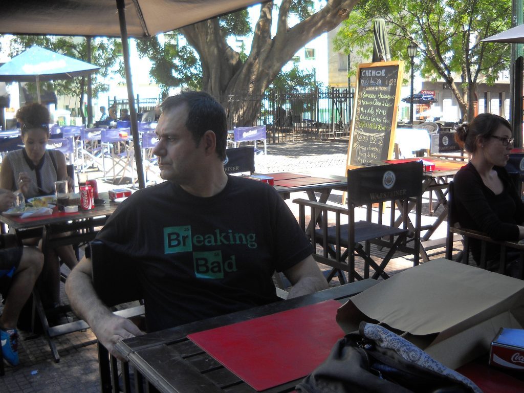 Aníbal Ricci Anduaga sentado en una terraza bajo sombrilla, con laptop y materiales de trabajo frente a él