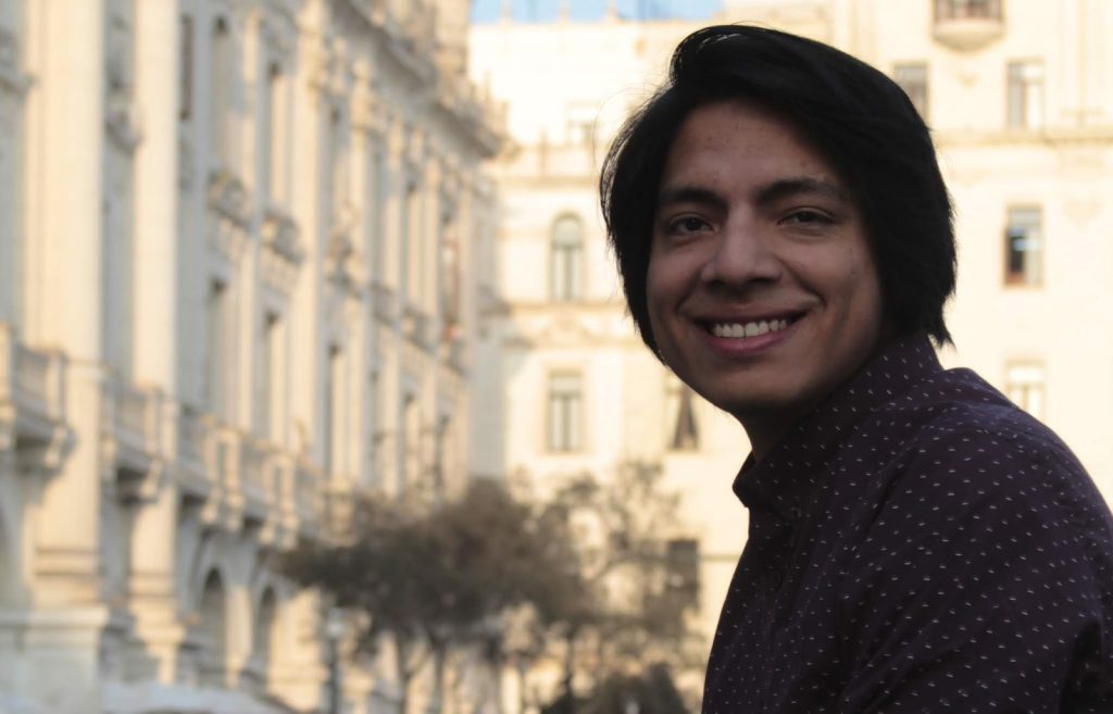 Julio Barco sonríe a la cámara con edificios de arquitectura clásica de fondo en ambiente urbano