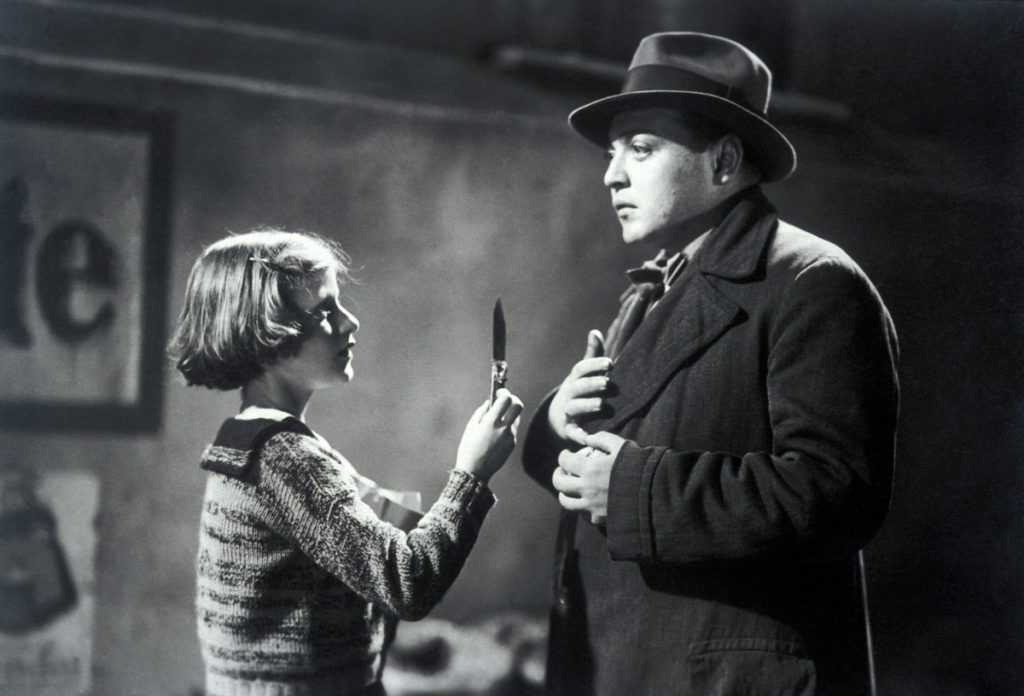 Hombre con sombrero y abrigo interroga a niña rubia en escena de cine clásico en blanco y negro