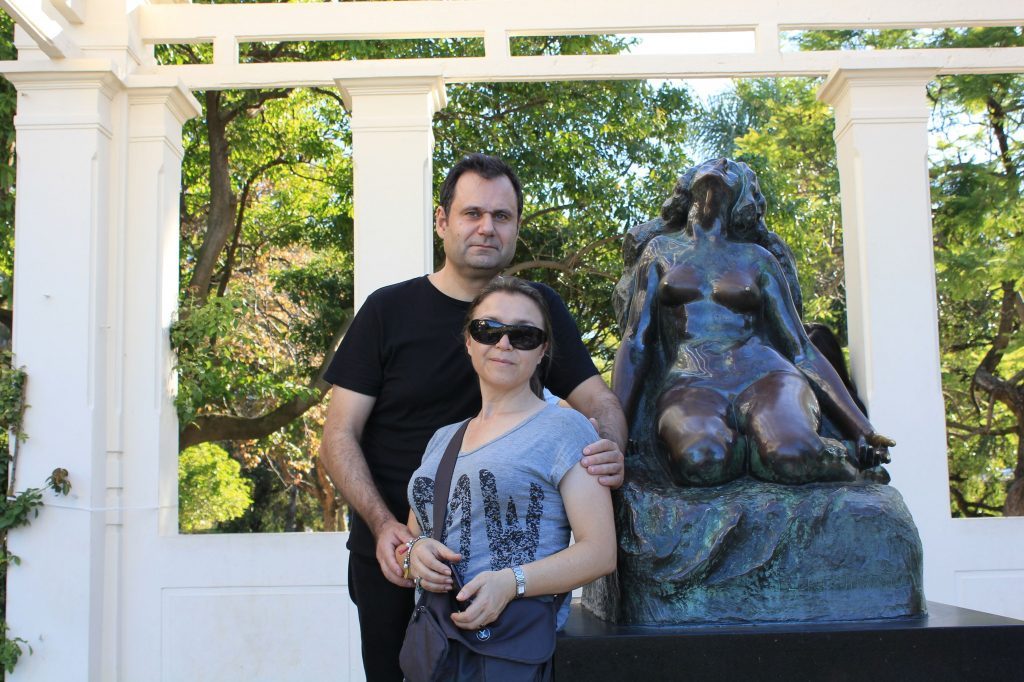 Aníbal Ricci con una niña frente a escultura de gorila en jardín con columnas blancas