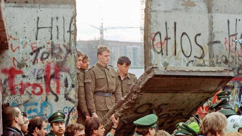 Soldados y civiles en el Muro de Berlín con grafitis, momento histórico de división entre Este y Oeste